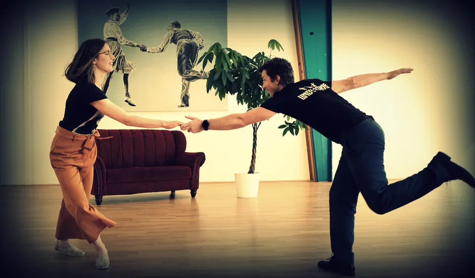 Una pareja baila en el estudio, él se inclina hacia delante y patea atrás